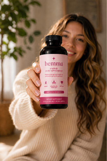 Woman holding a bottle of hemma liquid iron supplement at home